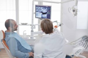 歯のレントゲン写真を見て説明をする歯科医師と説明を聞く患者