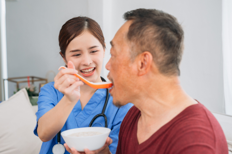 訪問診療で食べ物を食べるリハビリテーションをしている男性